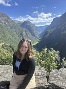 A woman smiles, with mountains behind her. 